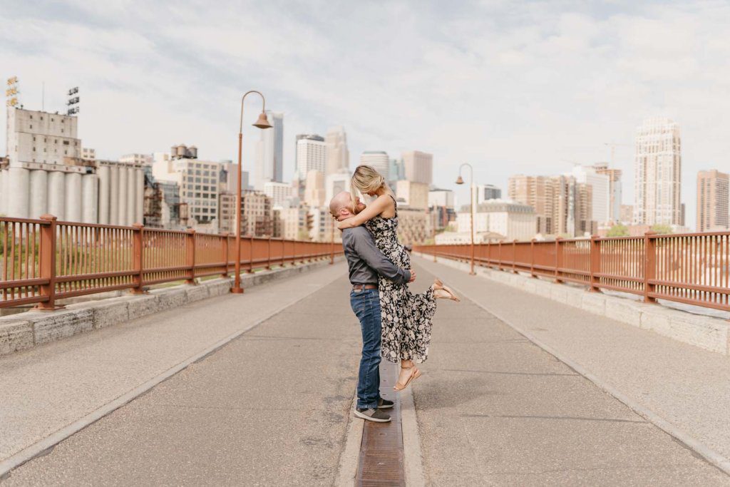 Engaged couple embracing on the stone arch bridge in Minneapolis during their engagement session