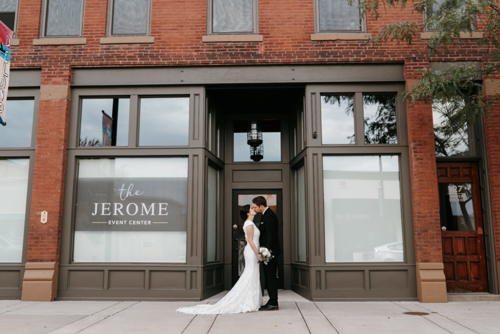 bride and groom kissing in front of the Jerome Event Center on their wedding day
