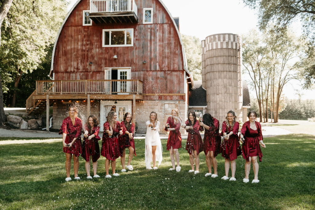 Bride popping champagne with her bridesmaids at her wedding venue: Howling Moon Weddings and Events. 