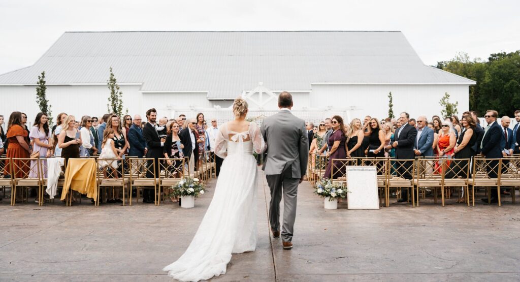 Bride walking down the aisle during her courtyard outdoor ceremony at Equestria West by Bavaria downs.