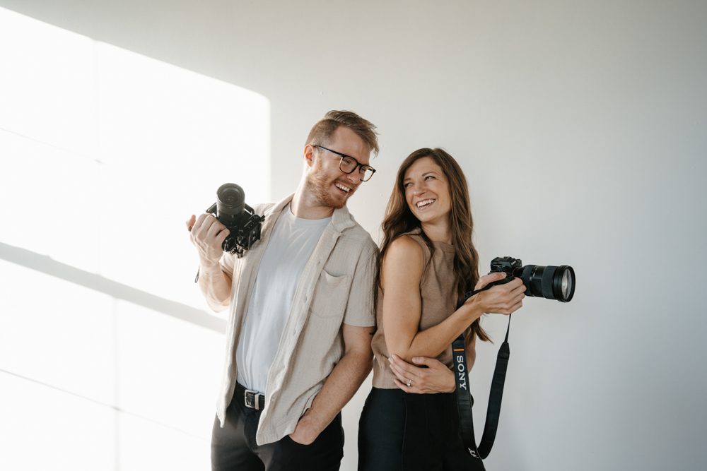 Luke and Halle, also known as lulle, is a husband and wife wedding photographer and videographer team based in Minneapolis Minnesota. This is a photo of them holding their camera gear at a studio in Minneapolis. They specialize in weddings and telling stories for couples.