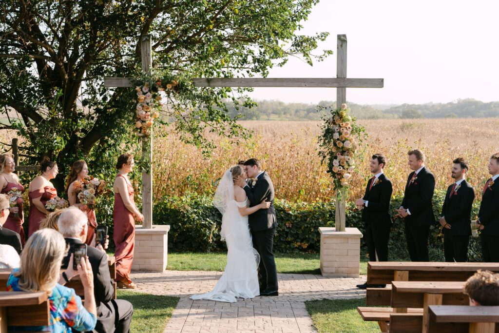 Bride and groom getting married outdoors at Legacy Hill Farm during their Minnesota Summer Wedding. Lulle Photo, a minnesota wedding photographer, photographed this candid moment during their first kiss.